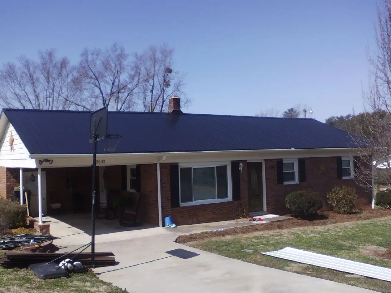 Finished dark blue metal roof on a brick ranch with a carport in Wentzville