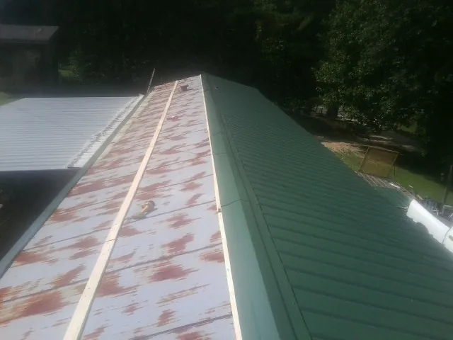 Old rusted panels beside newly installed green metal roofing — Wind Damage Roof Repair by Roofing Brothers in Wentzville