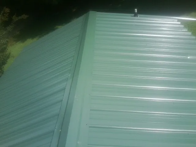 New green metal panels meeting at the ridge of a roof — Flat Roof Repair work by our crew in Wentzville