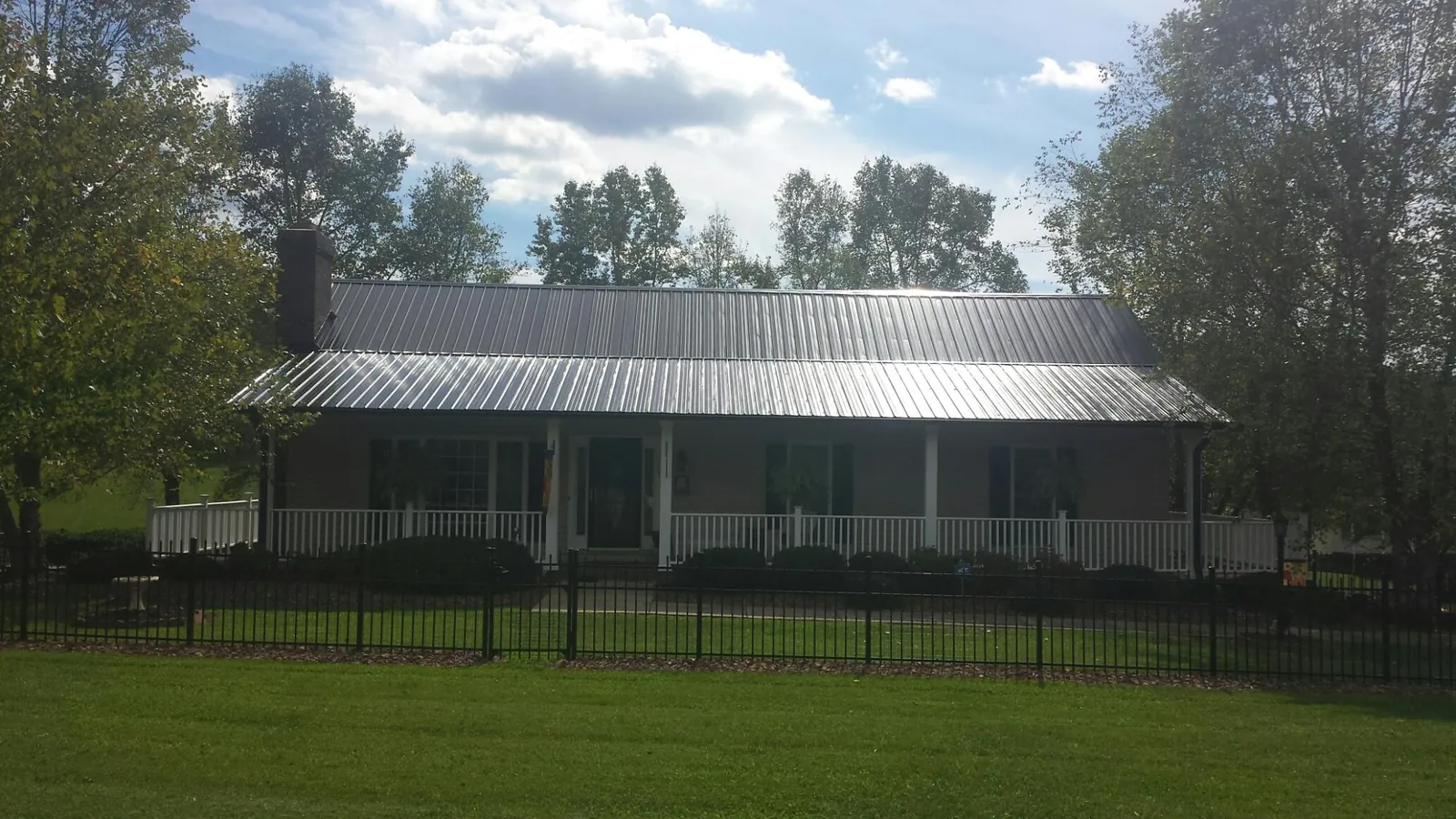 Gray metal roof on a brick ranch with a full width front porch — Gutter Guard Installation work by our crew in Wentzville