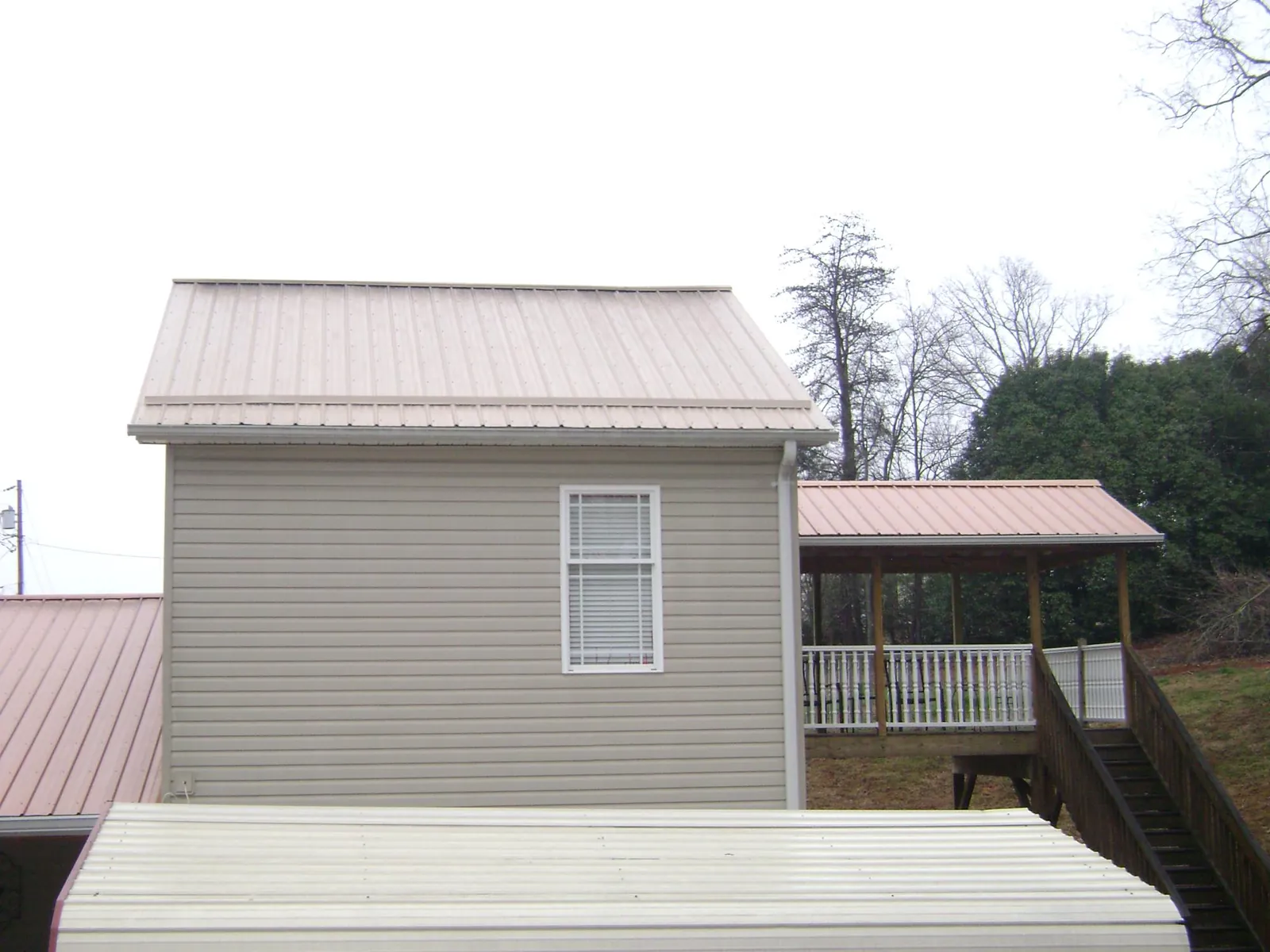 Tan metal roofs on a two story addition and attached porch, from a Roof Replacement job in Wentzville