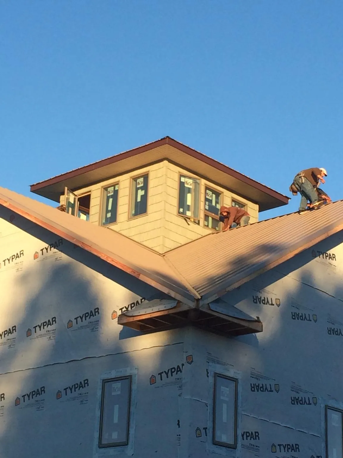 Roofers working around a rooftop cupola on a new metal roof at sunset — Roof Waterproofing in Wentzville by Roofing Brothers